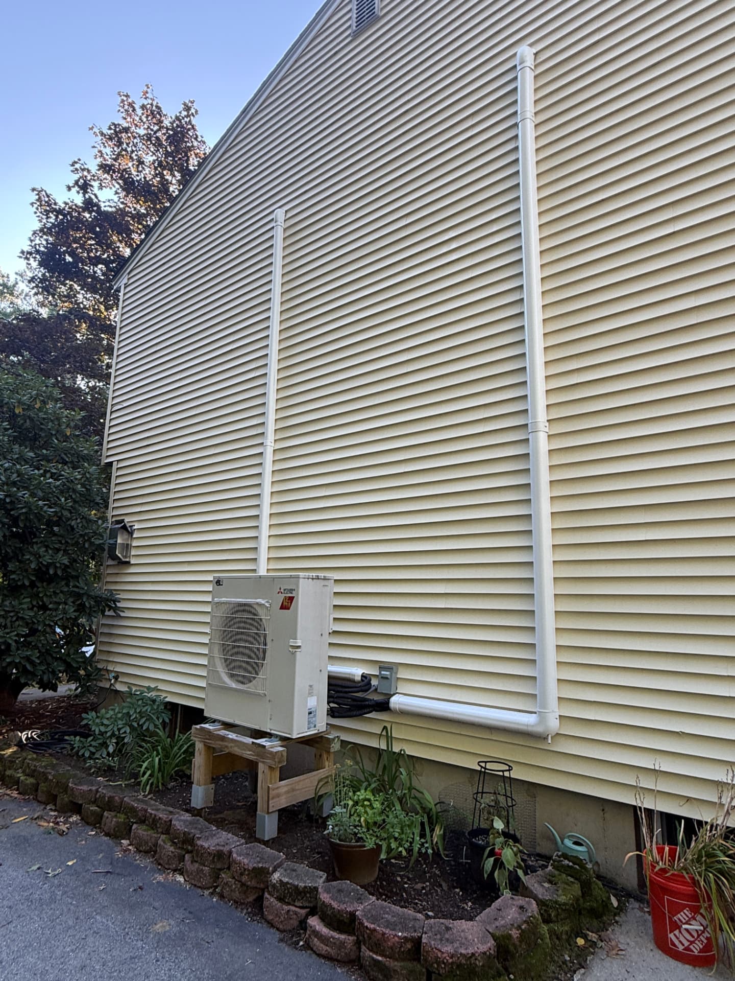 Mitsubishi condenser on a built stand with tall line-hide runs up the siding