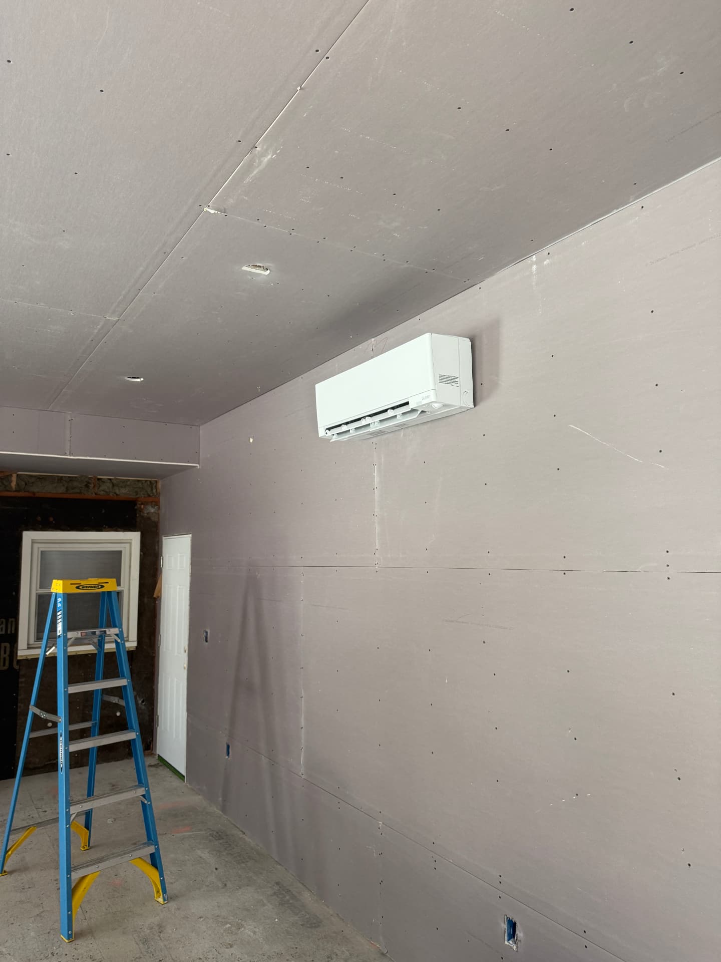 Mitsubishi wall unit mounted in a newly drywalled garage space