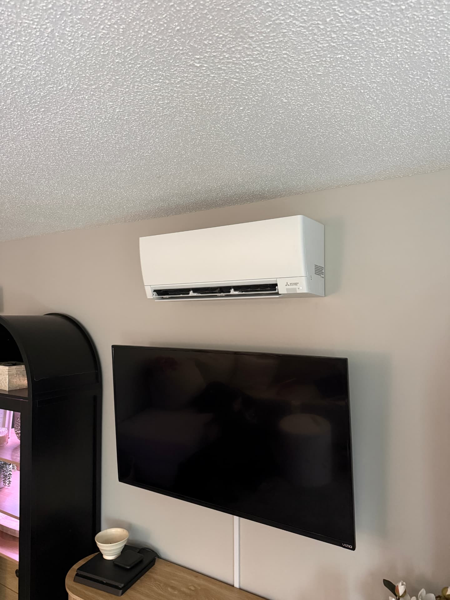Mitsubishi wall-mounted indoor unit installed above a TV in a living room