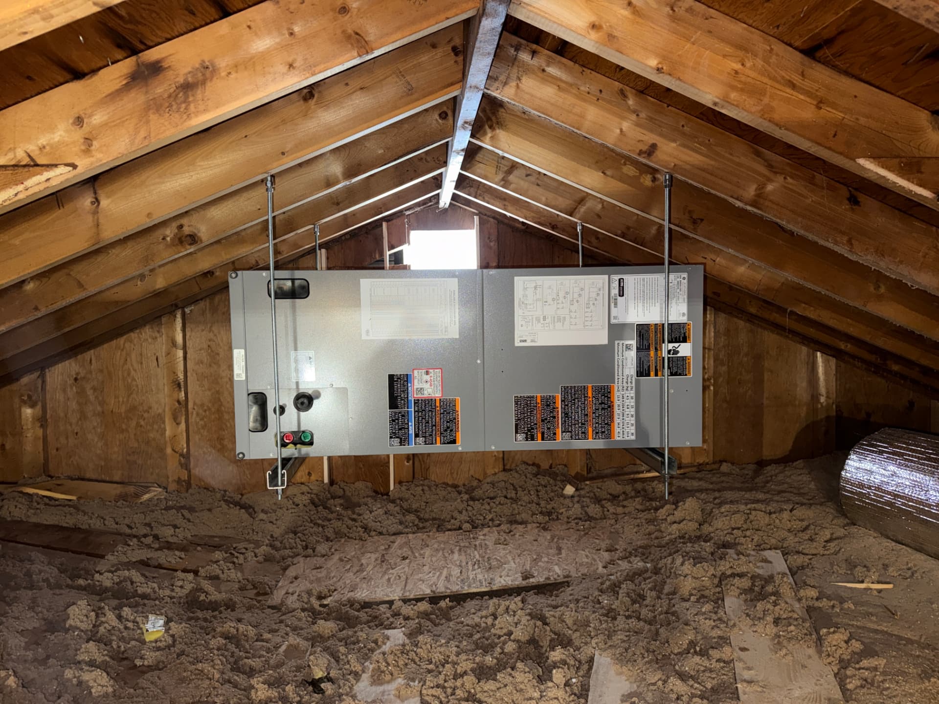 Air handler hung from attic rafters with threaded rod and level supports